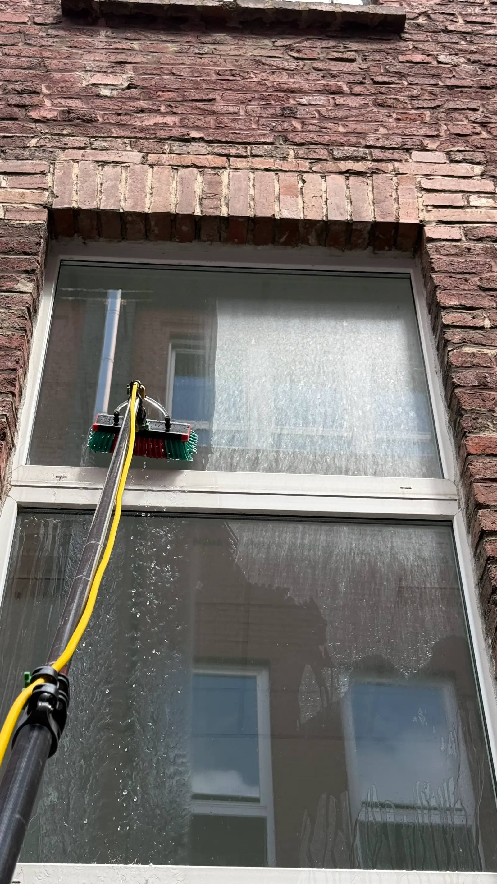 Glasreinigung am Wohngebäude mit Teleskopstange während der Arbeit